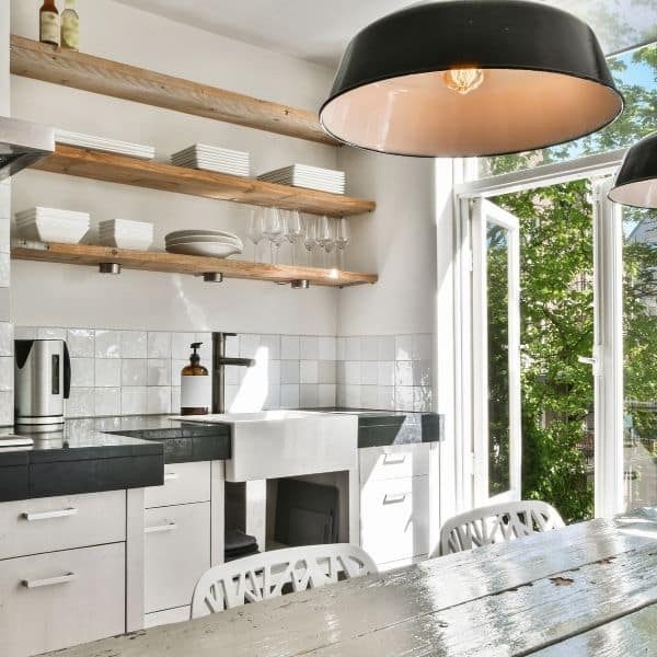 A clean modern kitchen with open shelving and a white tile backsplash.